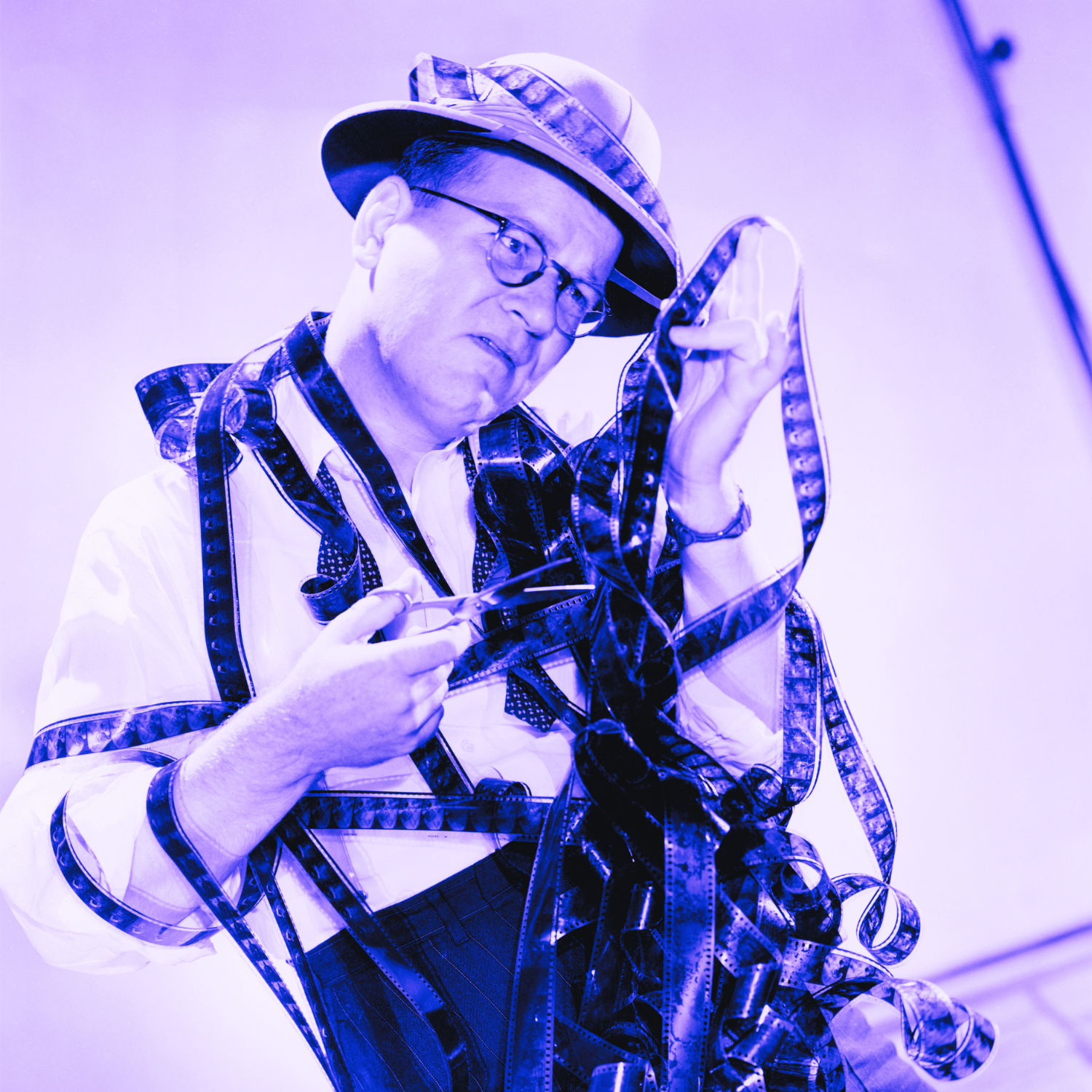 man with jumble of film stock editing it with a scizzors
